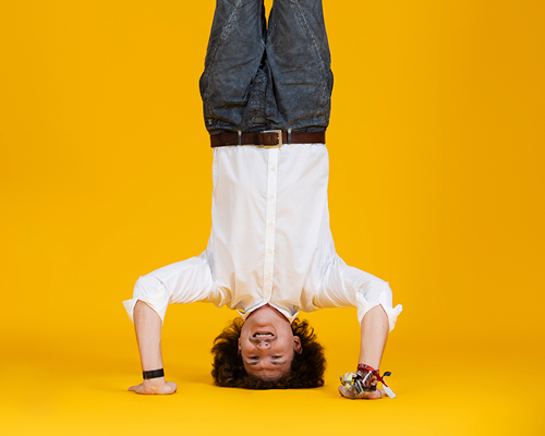 Employee doing a handstand on orange background and spreading the LOGICspirit